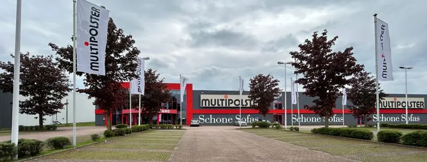 Vor dem Möbelhaus Multipolster in Dortmund stehen Fahnen vor einem modernen Gebäude mit der Aufschrift Schöne Sofas.