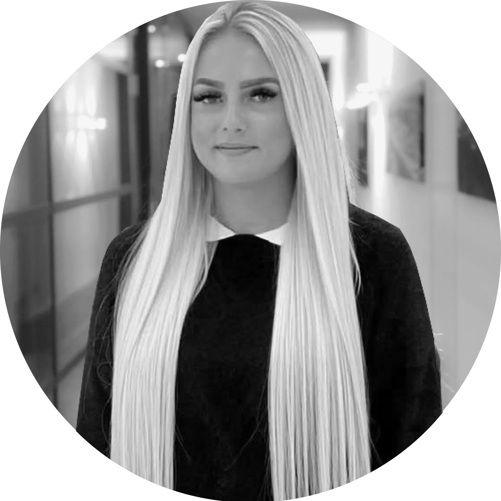 Frau mit langen, blonden Haaren und schwarzem Oberteil in einem Innenraum.
