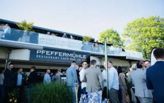 Menschenmenge beim Retailer Meeting 2025 vor dem Restaurant Pfeffermühle, umgeben von Pflanzen und einer Terrasse.